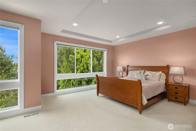 bedroom with light carpet, a tray ceiling, recessed lighting, and baseboards