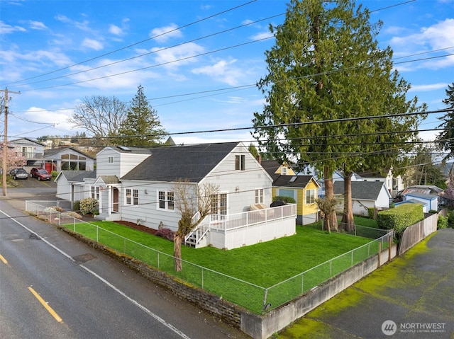 view of front of property with a fenced front yard, a front lawn, and roof with shingles
