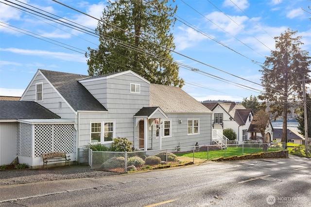 view of front of house featuring a shingled roof and a fenced front yard