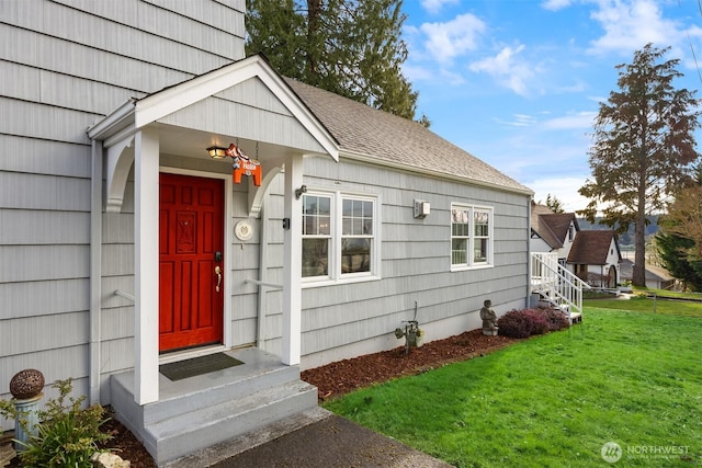 property entrance with a lawn and roof with shingles