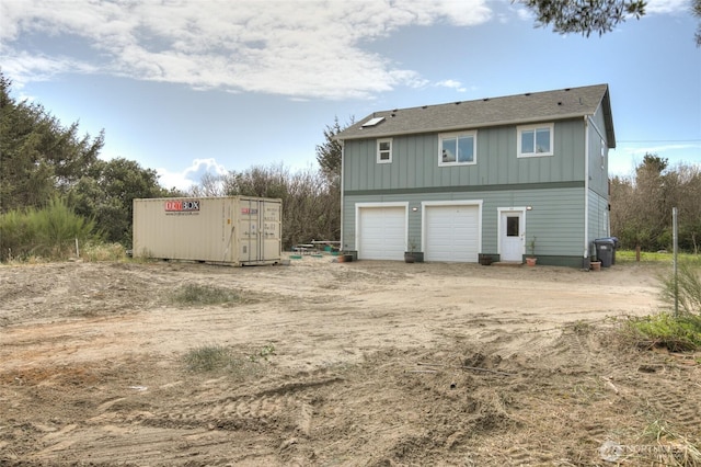 33 4th Ave, Ocean Shores, WA 98569 - back of property with dirt driveway, an attached garage, and board and batten siding