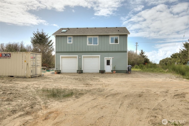 33 4th Ave, Ocean Shores, WA 98569 - back of house featuring board and batten siding, an attached garage, and dirt driveway