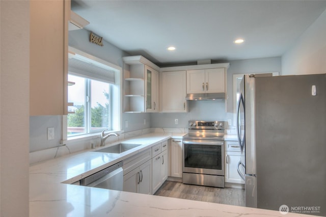 33 4th Ave, Ocean Shores, WA 98569 - kitchen with stainless steel appliances, under cabinet range hood, a sink, light stone counters, and white cabinets