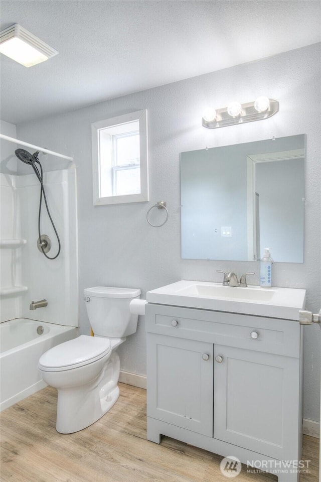 33 4th Ave, Ocean Shores, WA 98569 - bathroom featuring toilet, vanity, wood finished floors, a textured ceiling, and tub / shower combination