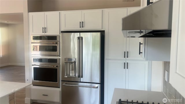 6414 213th Avenue Ct E, Bonney Lake, WA 98391 - kitchen with stainless steel appliances, white cabinetry, exhaust hood, and wood finished floors
