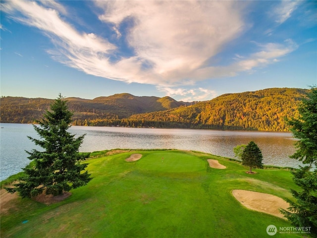 water view featuring a heavily wooded area, mountains, and a local golf course