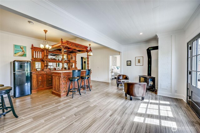 8494 NE Odd Fellows Rd, Bainbridge Island, WA 98110 - interior space with bar, crown molding, a wood stove, freestanding refrigerator, and light wood-style flooring