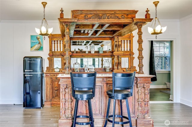 bar featuring indoor wet bar, decorative light fixtures, a notable chandelier, and wood finished floors