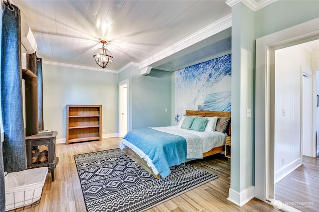 bedroom with a wood stove, wood finished floors, a notable chandelier, and ornamental molding