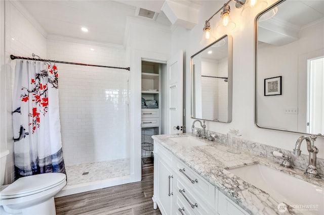 bathroom featuring toilet, tiled shower, a sink, and wood finished floors