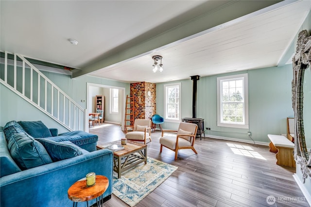 living area with stairs, baseboards, wood finished floors, and a wood stove
