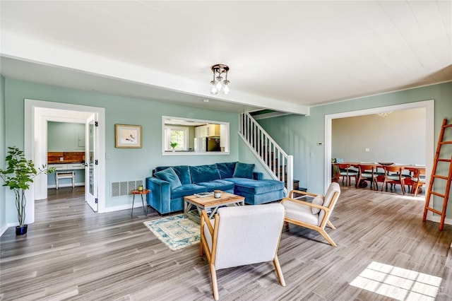living area featuring baseboards, visible vents, wood finished floors, and stairway