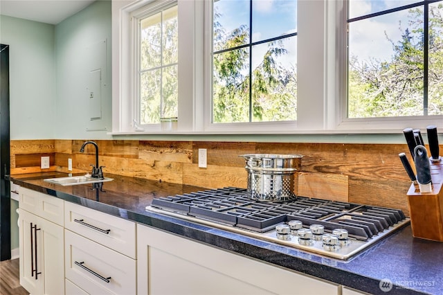 kitchen featuring a sink, stainless steel gas cooktop, backsplash, and white cabinets