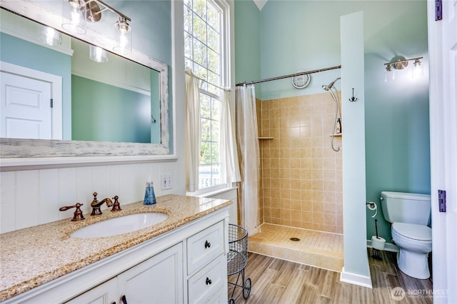 full bathroom with toilet, a shower stall, wood finished floors, and plenty of natural light