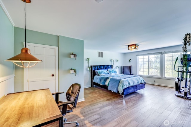 bedroom with visible vents, baseboards, and wood finished floors