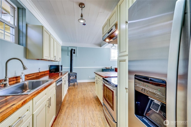 8494 NE Odd Fellows Rd, Bainbridge Island, WA 98110 - kitchen featuring a wood stove, wooden counters, light wood-type flooring, a sink, and appliances with stainless steel finishes