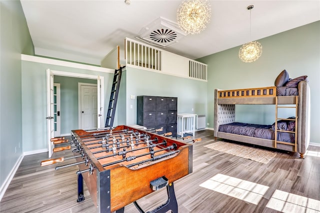 rec room with baseboards, a chandelier, and wood finished floors