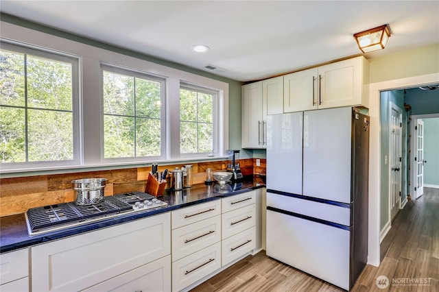 kitchen featuring visible vents, freestanding refrigerator, white cabinets, and dark countertops