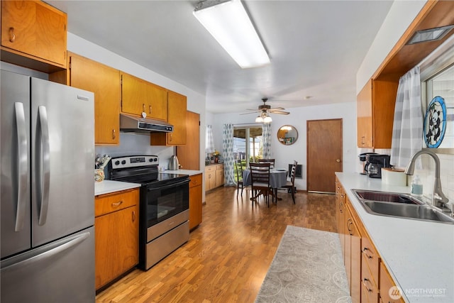 2824 Pacific Ave, Hoquiam, WA 98550 - kitchen featuring light countertops, a sink, brown cabinetry, under cabinet range hood, and stainless steel appliances