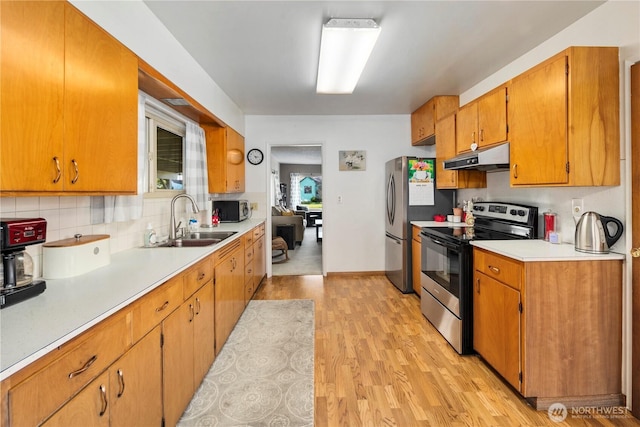 2824 Pacific Ave, Hoquiam, WA 98550 - kitchen with light countertops, a sink, light wood-style flooring, under cabinet range hood, and stainless steel appliances