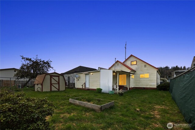 2824 Pacific Ave, Hoquiam, WA 98550 - back of property at dusk with an outbuilding, fence, a storage unit, a lawn, and a vegetable garden