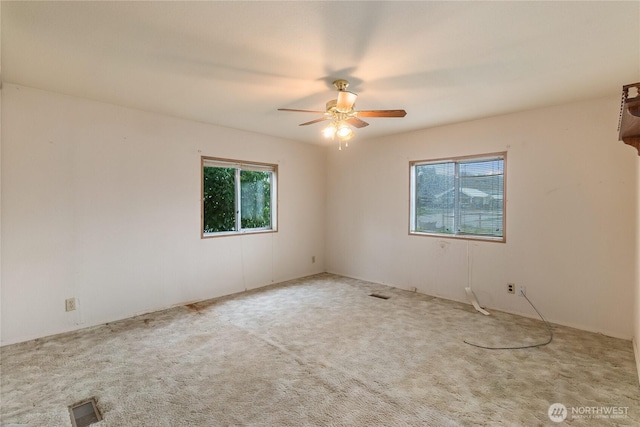 spare room featuring ceiling fan, visible vents, and carpet