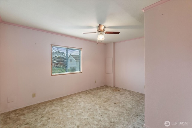 carpeted empty room featuring a ceiling fan and crown molding