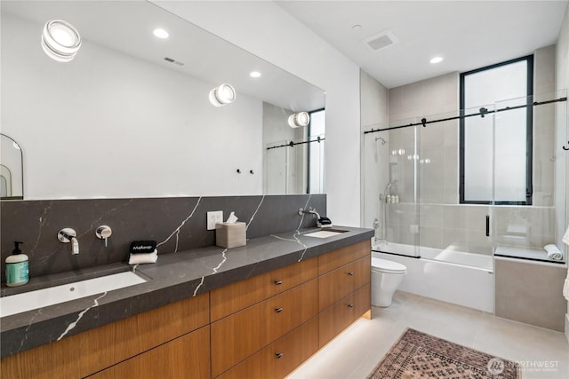bathroom with toilet, a sink, enclosed tub / shower combo, and double vanity