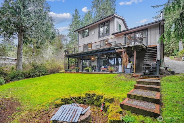 rear view of house with a lawn, stairway, a deck, and a patio area