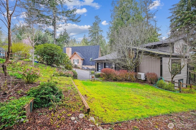 view of yard featuring ac unit and aphalt driveway
