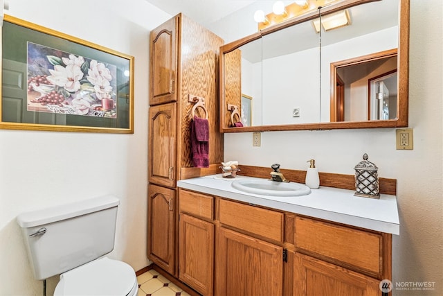 bathroom with toilet, vanity, and tile patterned floors