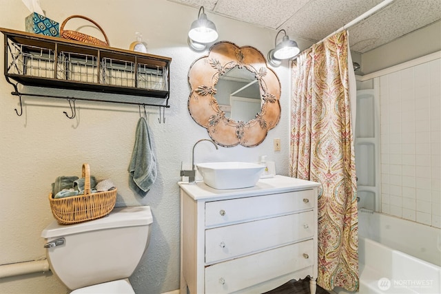 bathroom with a drop ceiling, shower / bathtub combination with curtain, toilet, and vanity
