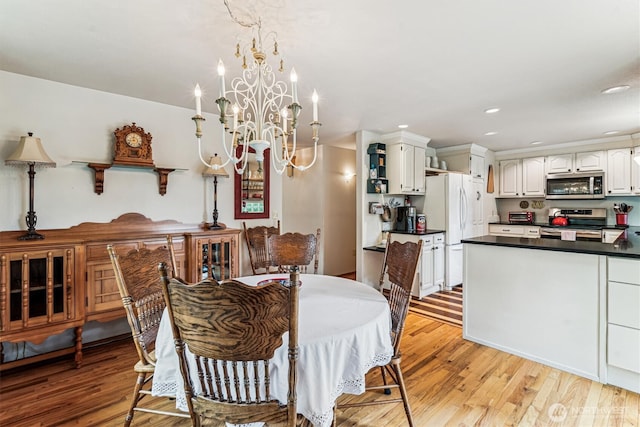 dining space featuring light wood-style flooring, recessed lighting, and an inviting chandelier