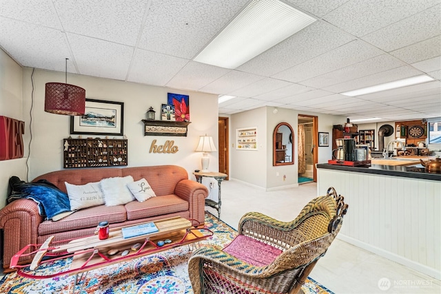 living room featuring baseboards and a paneled ceiling