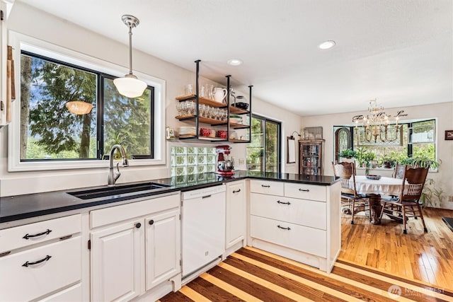 kitchen featuring a sink, dark countertops, light wood-style floors, dishwasher, and white cabinets