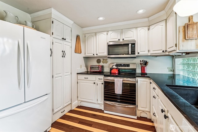 kitchen featuring white cabinetry, recessed lighting, light wood-type flooring, dark countertops, and appliances with stainless steel finishes