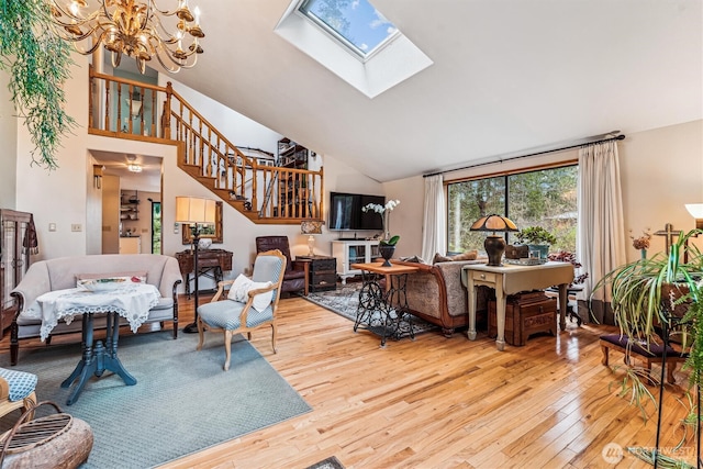 living area featuring high vaulted ceiling, a chandelier, a skylight, stairway, and wood-type flooring