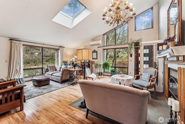 living room featuring an inviting chandelier, high vaulted ceiling, a skylight, light wood-style floors, and a wall mounted air conditioner