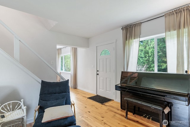 foyer entrance featuring stairs, light wood-style flooring, and baseboards