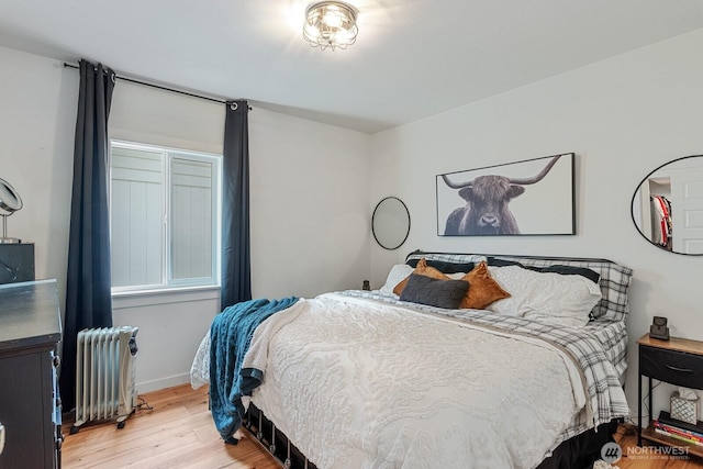 bedroom featuring baseboards, light wood-style flooring, and radiator heating unit