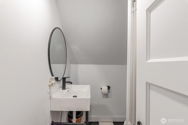 bathroom featuring lofted ceiling and a sink