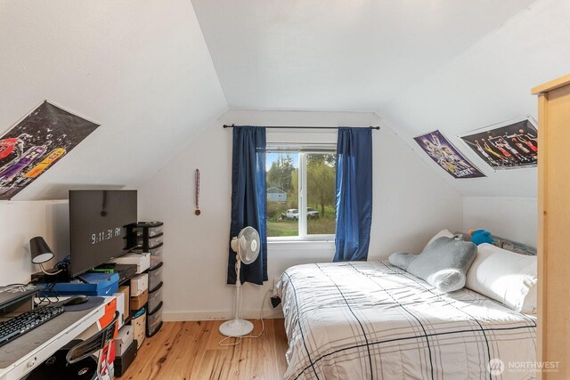 bedroom with baseboards, lofted ceiling, and wood finished floors