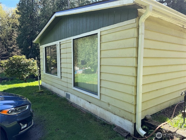 view of side of property with a yard and crawl space