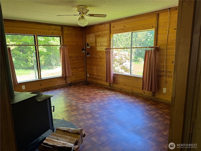 empty room featuring a textured ceiling, wooden walls, and a healthy amount of sunlight