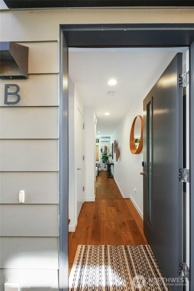 corridor with baseboards and wood finished floors