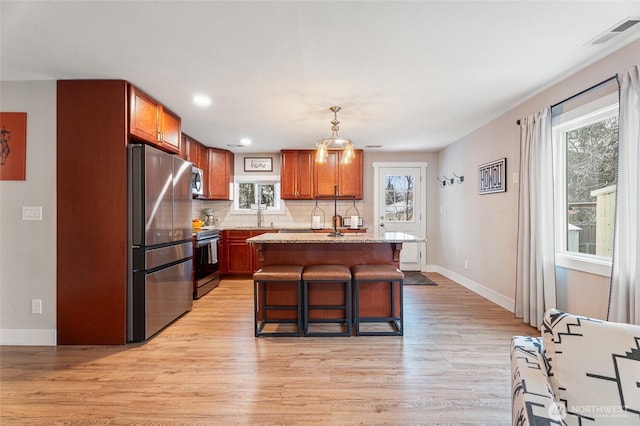 207 Harmon St, Waitsburg, WA 99361 - kitchen with a kitchen breakfast bar, light wood-type flooring, stainless steel appliances, visible vents, and decorative backsplash