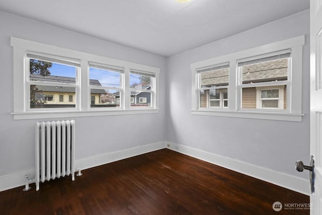 902 Wood Ave, Sumner, WA 98390 - unfurnished room featuring dark wood-type flooring, radiator, and baseboards