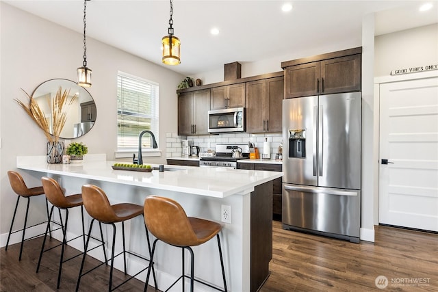 441 Lupine Ln SW, Ocean Shores, WA 98569 - kitchen with dark brown cabinets, appliances with stainless steel finishes, a sink, dark wood-style floors, and backsplash