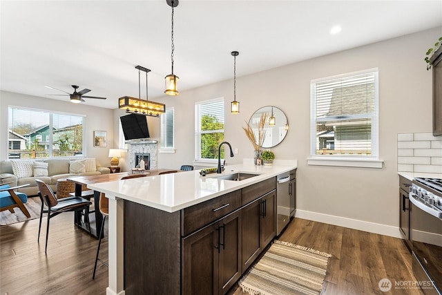 441 Lupine Ln SW, Ocean Shores, WA 98569 - kitchen featuring stainless steel appliances, a ceiling fan, a stone fireplace, dark brown cabinetry, and a sink