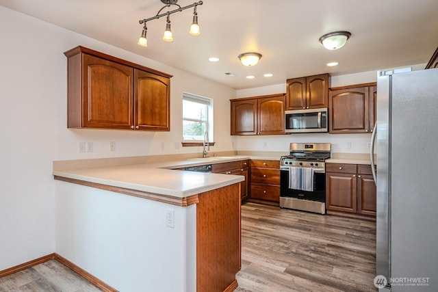 402 Easy St SE, Rainier, WA 98576 - kitchen featuring a sink, a peninsula, light wood-type flooring, stainless steel appliances, and baseboards